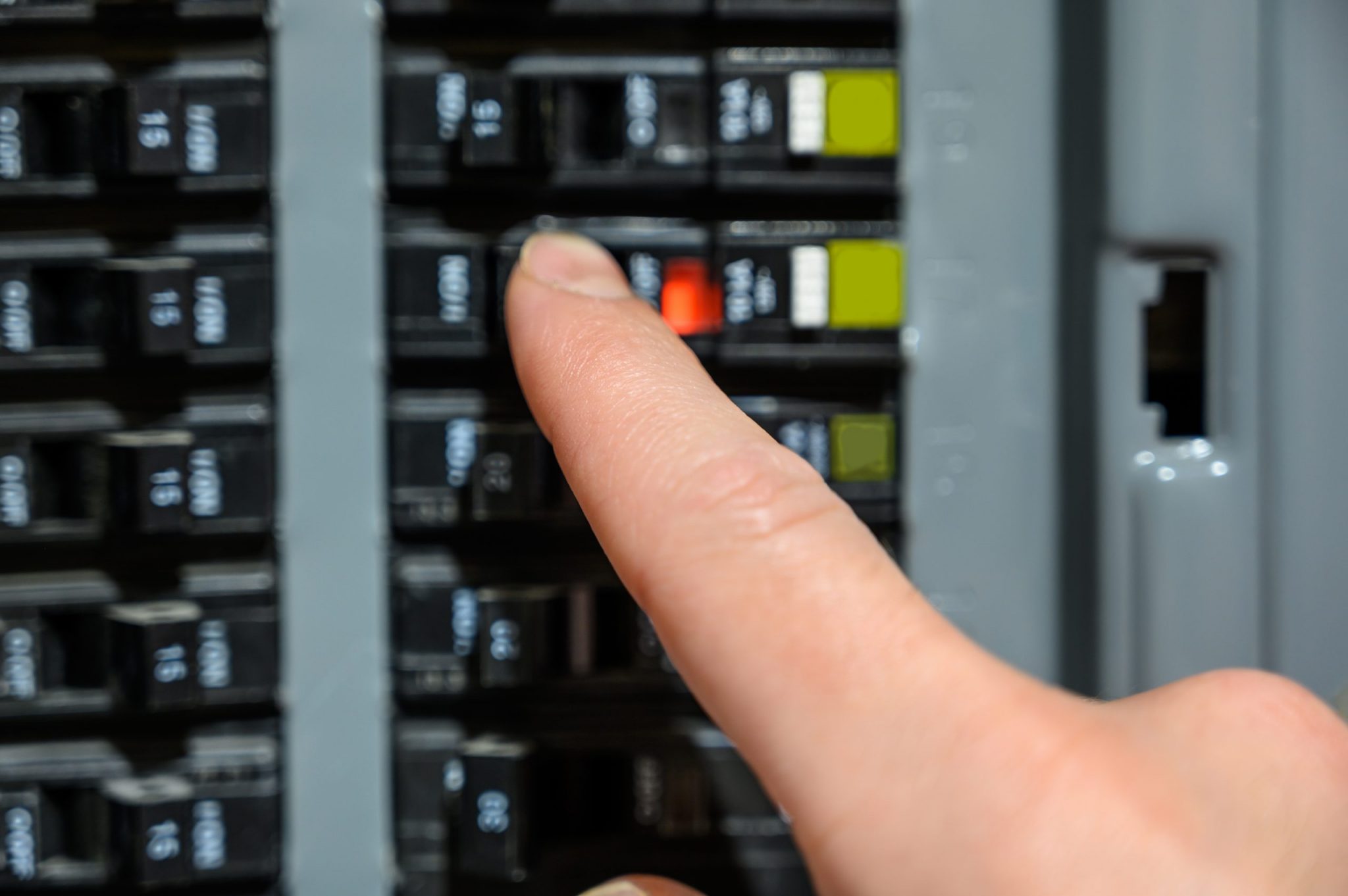 Finger resetting a tripped breaker in residential house electric box
