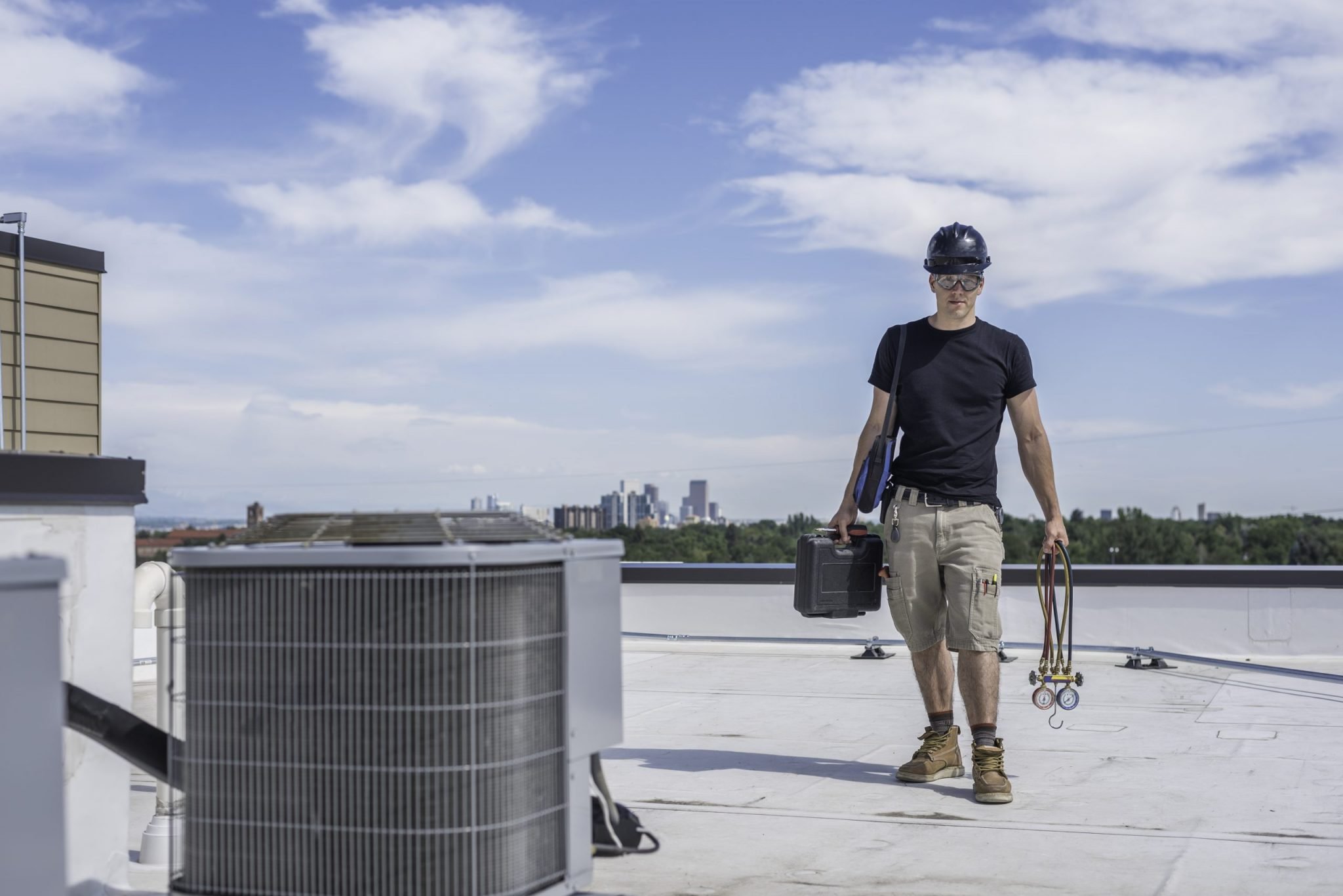 Hvac technician standing by an air conditioner condensing unit on a roof