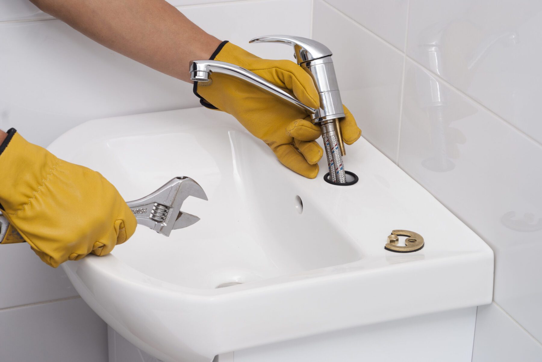 Installing Faucet Gloved hands installing faucet into sink and wrench in other hand