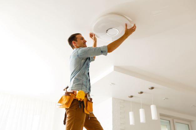 Electrician installing light on ceiling