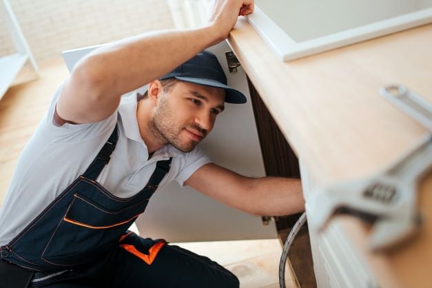 Plumber inspecting situation under sink.