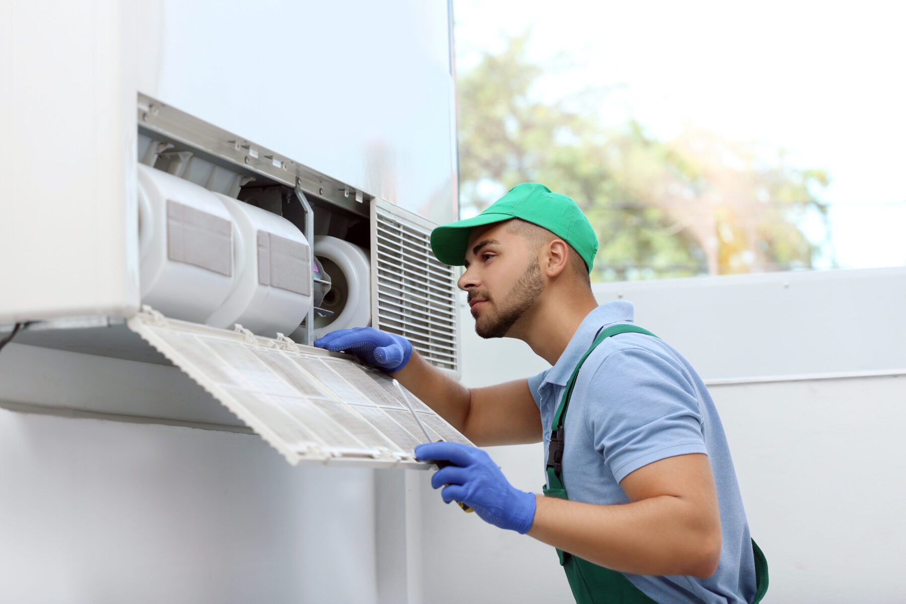 Professional technician maintaining modern air conditioner indoors
