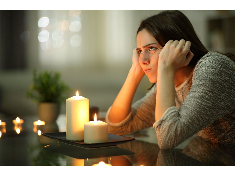 Person upset leaned on table with candles on, while on a power outage.