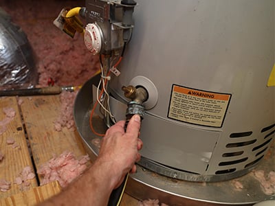 A man inspecting a water heater for repair