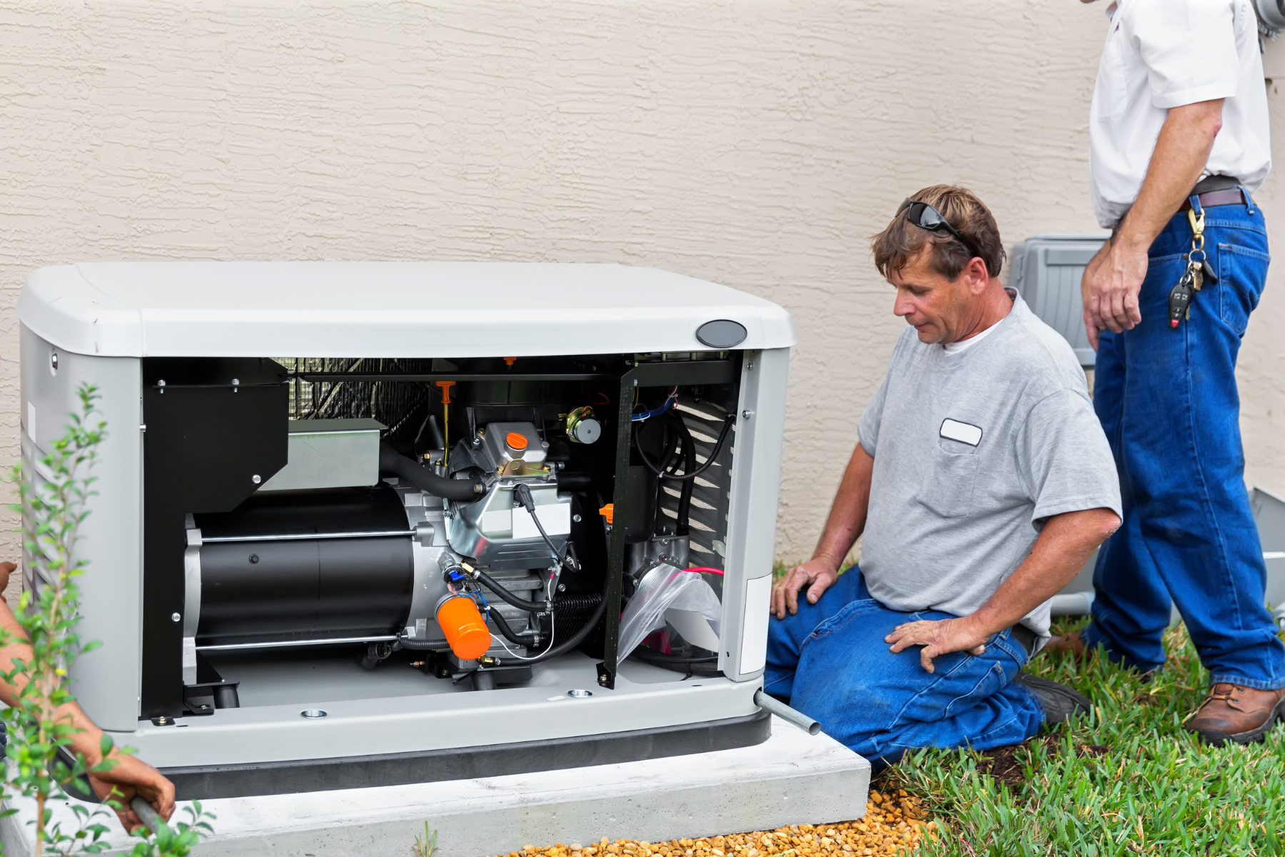A technician kneels beside an open generator, inspecting its internal components. The image shows the engine parts, with wires and a motor visible. The technician is likely performing maintenance or repairs.