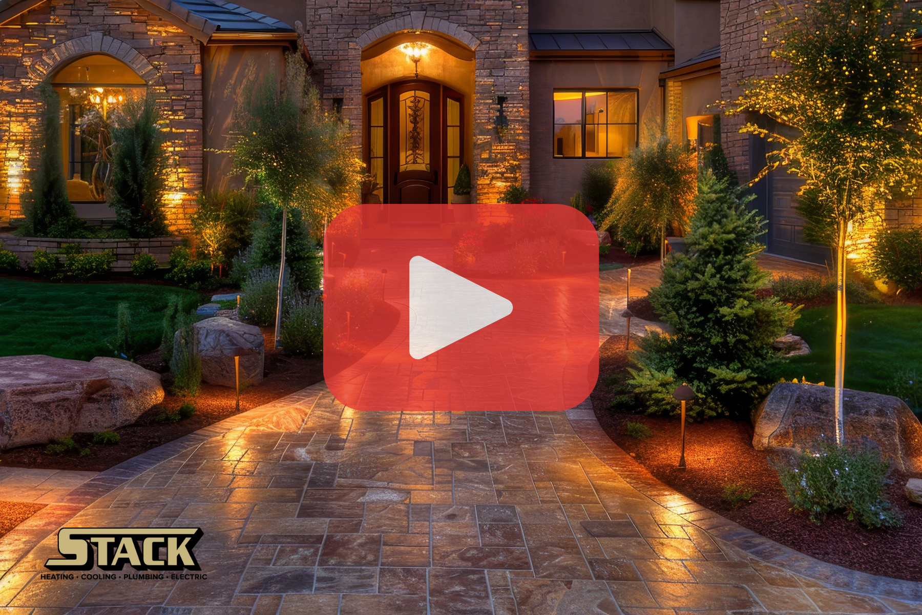 A beautifully illuminated home exterior and pathway at night, with warm lighting and a Stack video overlay.