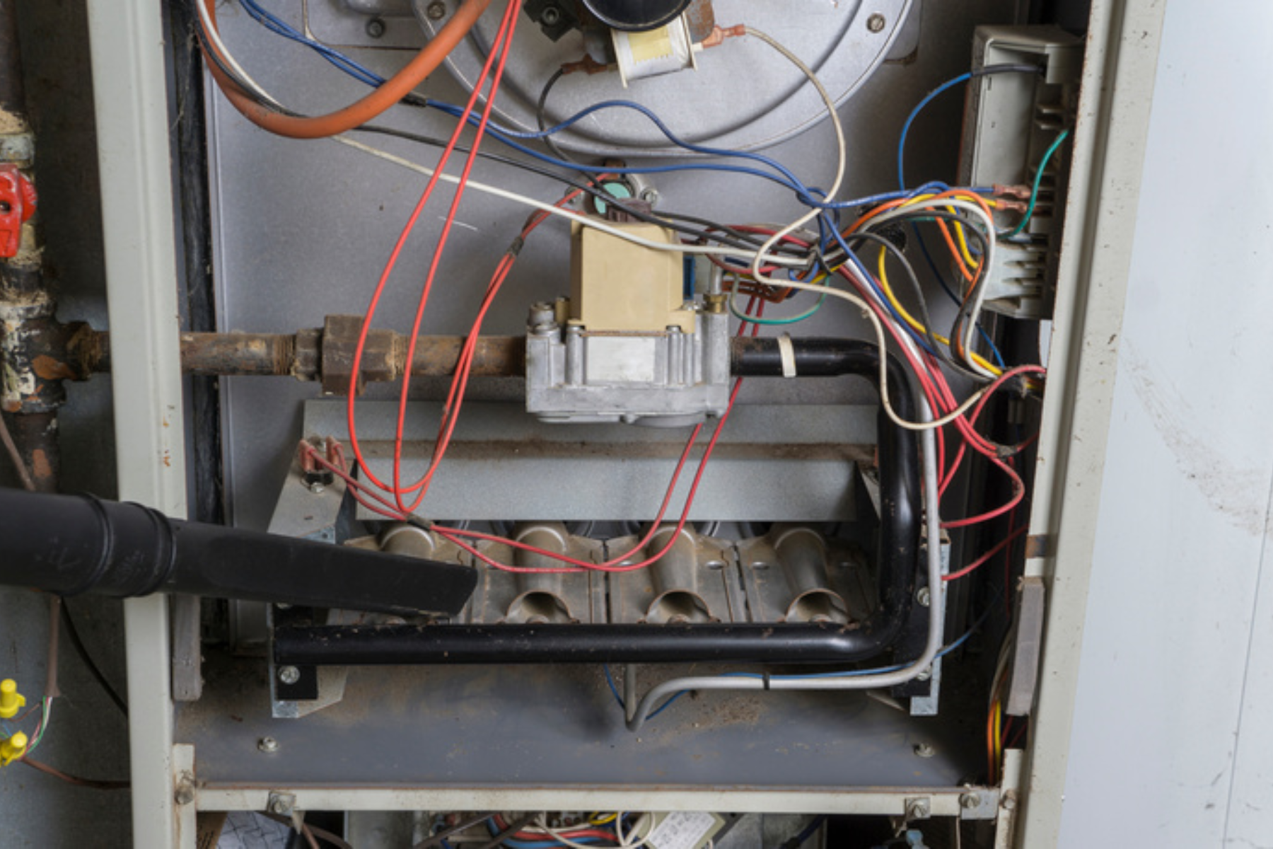 Exposed wiring and components of a gas furnace during cleaning or maintenance.
