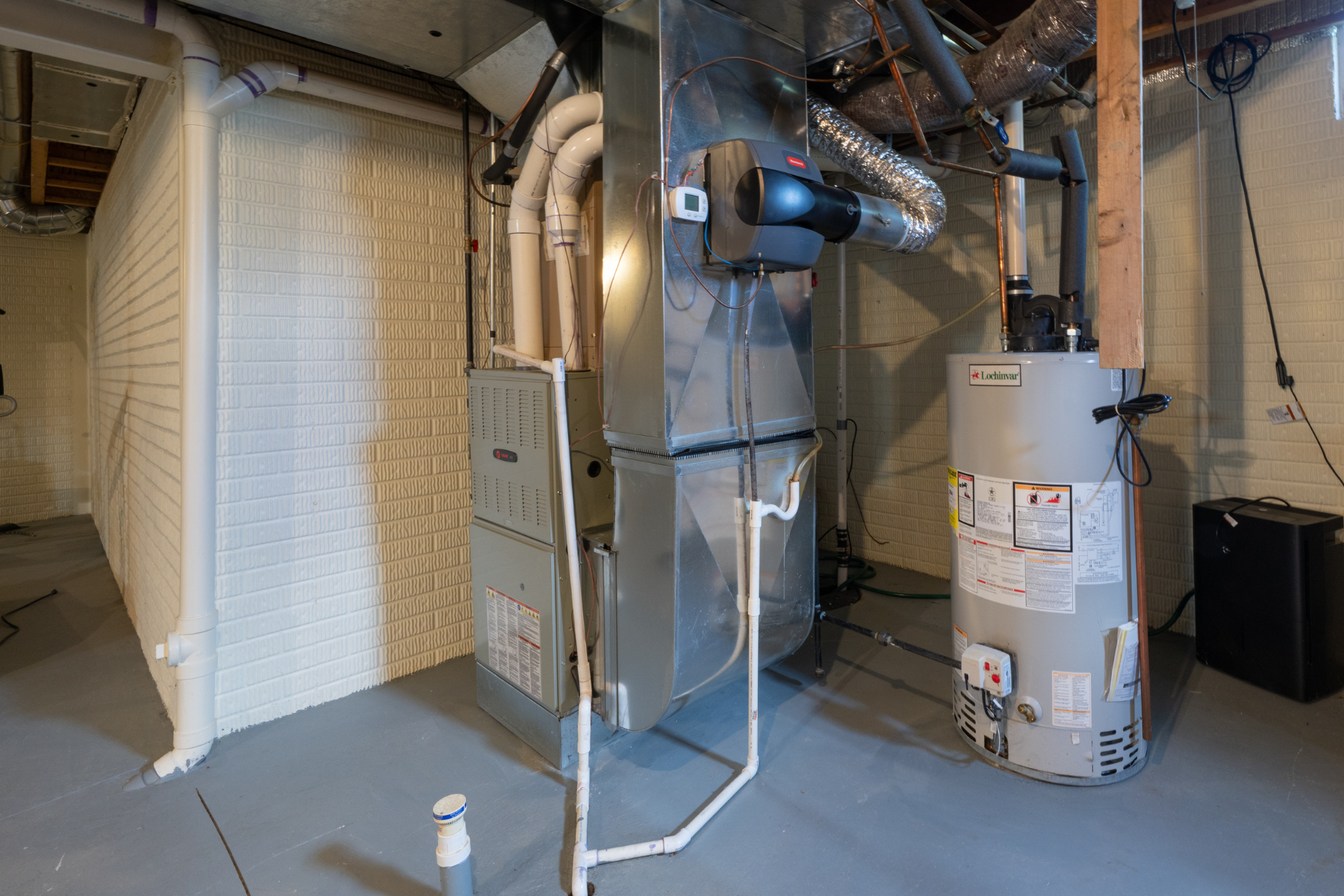 A residential furnace system and water heater installed in a basement utility area.