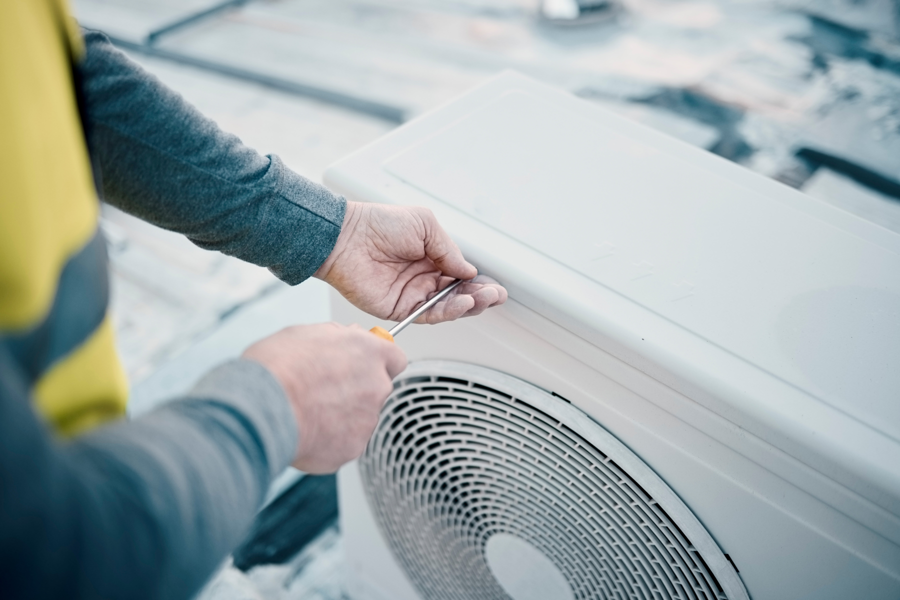 A technician uses a multimeter to test the electrical components of an outdoor air conditioning unit.