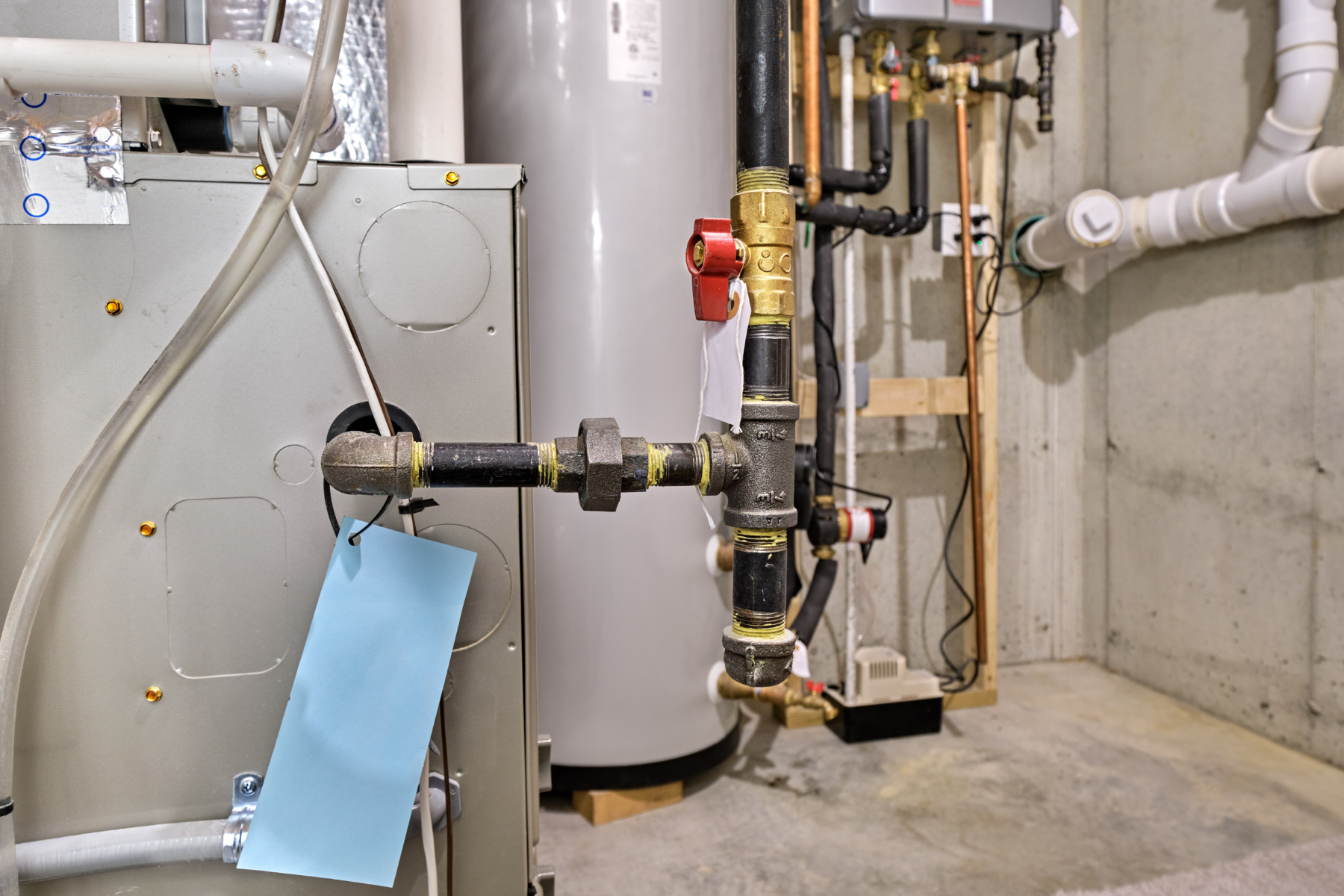 Close-up of gas and water piping connected to a heating system with shutoff valves.