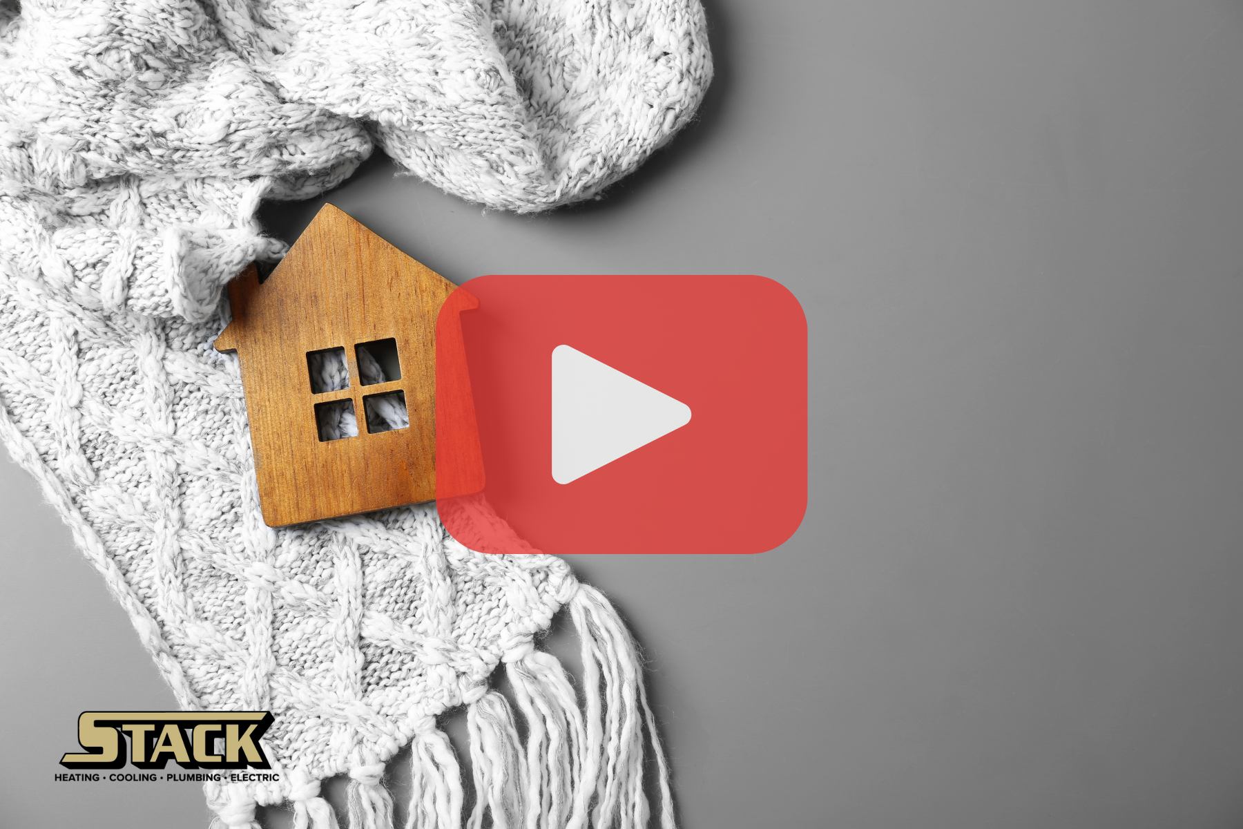 A small wooden house figurine sits on top of a cozy, knitted white blanket, symbolizing warmth and home comfort.