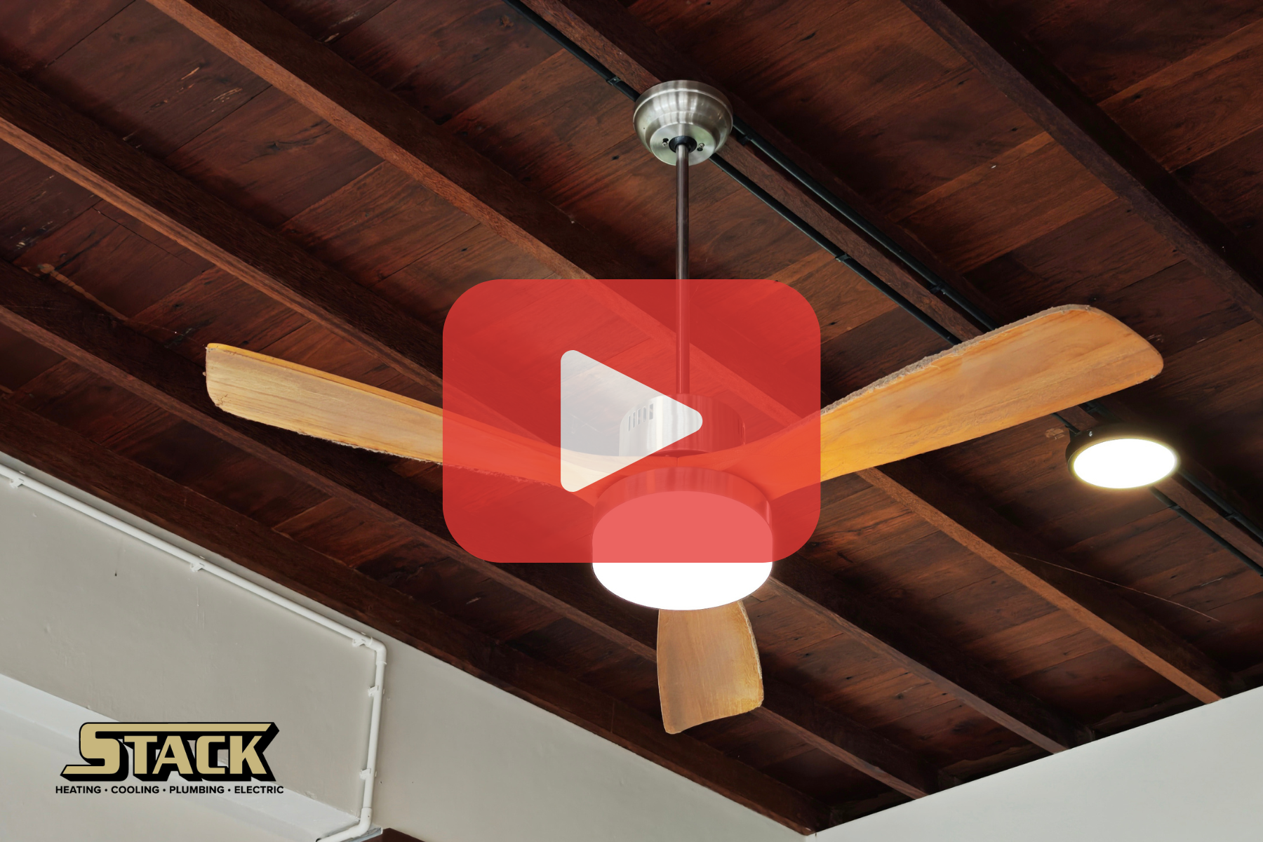 Brown ceiling fan on wooden ceiling with red play button.