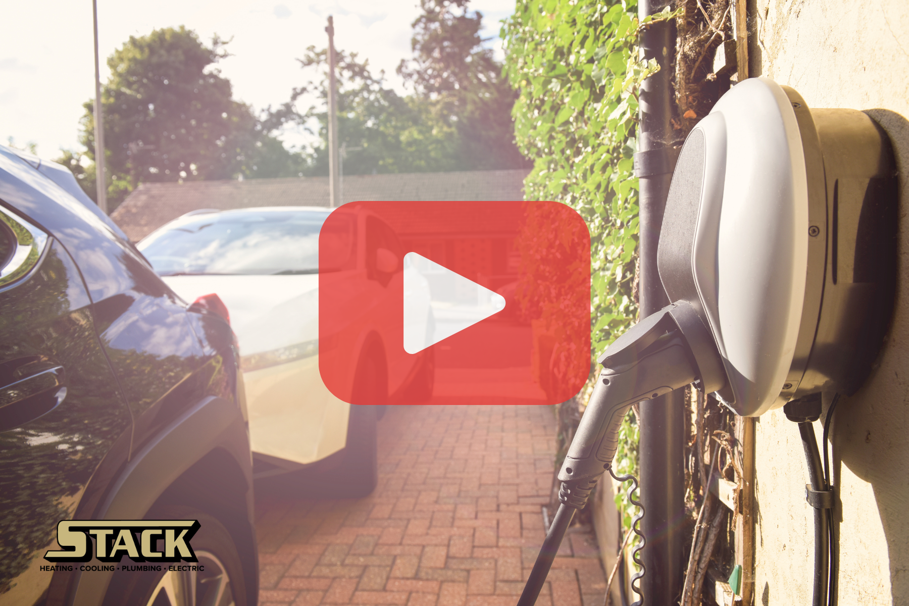 Two cars are parked and one is being charged with and EV charger. Red play buttom overlay