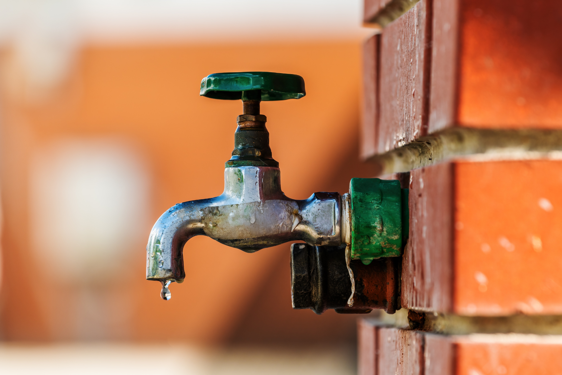 Close up of spigot outdoors on brick wall.