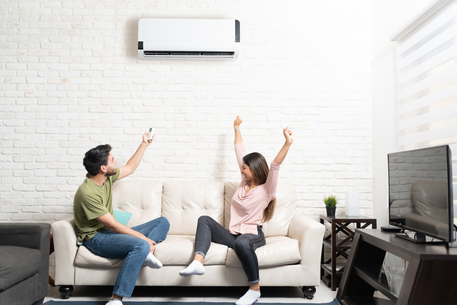 Man and woman sitting on couch celebratinf that mini split AC turns on.