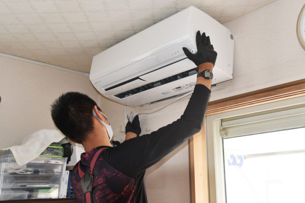Man inspecting AC on wall.
