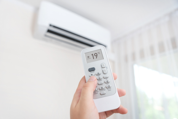 Close up of AC remote and AC on wall.