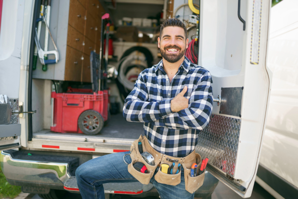 Electrician smiling. With the truck full of electrical equipment. 